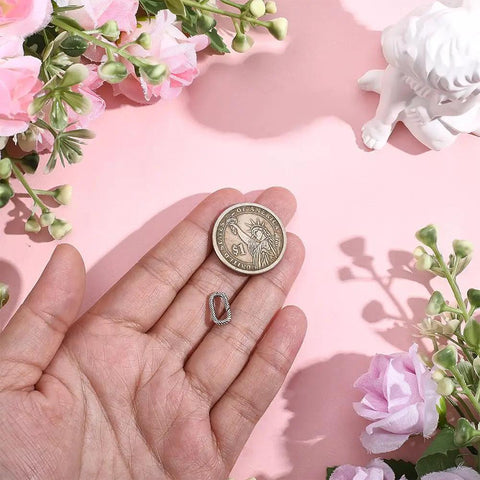 Hand holding textured 925 sterling silver oval spring gate rings carabiner clips with a coin for size comparison.