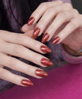 Close-up of hands with Semi Cured Gel Nail Strips Real Gel Nail Polish UV Wraps, glitter cat-eye warm orange finish.