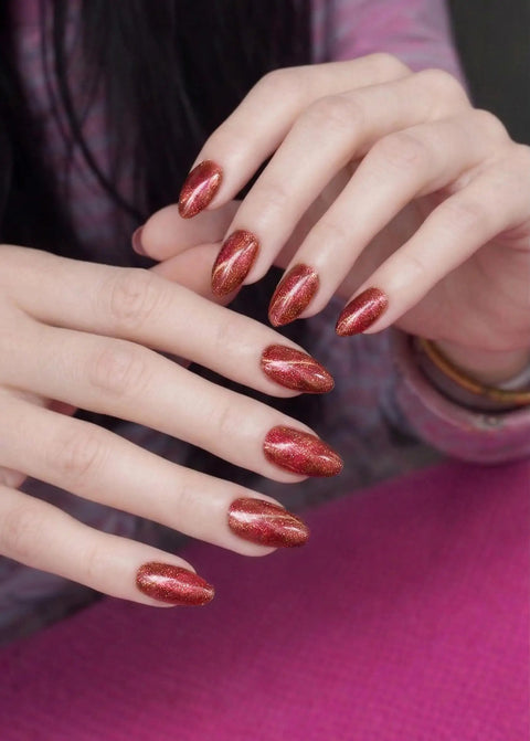 Close-up of hands with Semi Cured Gel Nail Strips Real Gel Nail Polish UV Wraps, glitter cat-eye warm orange finish.