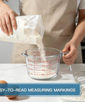 Person pouring flour into Must Have Glass Measuring Cups Set With Lids, 4 Piece Borosilicate Kitchen Measuring Cups in 4 Cup Size