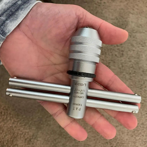 Hand holding adjustable ratcheting T handle tap wrench for fast accurate thread tapping M6 to M14, dual handles visible