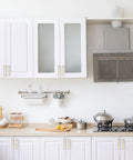 10 Pack 5 Inch Brushed Gold Cabinet Pulls Zinc Alloy Handles installed on white kitchen cabinets with a modern stove and range hood.