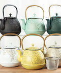 Assorted cast iron teapots including "Cast Iron Teapot With Stainless Steel Infuser For Stovetop Brewing, 32 Oz Capacity, Enamel Interior, Leaf Design, Light Green Kettle For Easy Pour And Rich Flavor" on display.