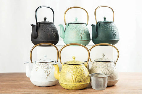 Assorted cast iron teapots including "Cast Iron Teapot With Stainless Steel Infuser For Stovetop Brewing, 32 Oz Capacity, Enamel Interior, Leaf Design, Light Green Kettle For Easy Pour And Rich Flavor" on display.
