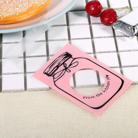 100 Pcs Lovely Plastic Cookies Gift Packaging Bags For Party Supplies Pink Food Grade Safe And Durable Ideal For Weddings Birthdays And Celebrations Everywhere shown with dessert and cherries on a tile surface.