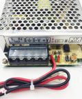 Close-up of a compact 60W switching power supply with UPS and charge function, input-output connections visible.