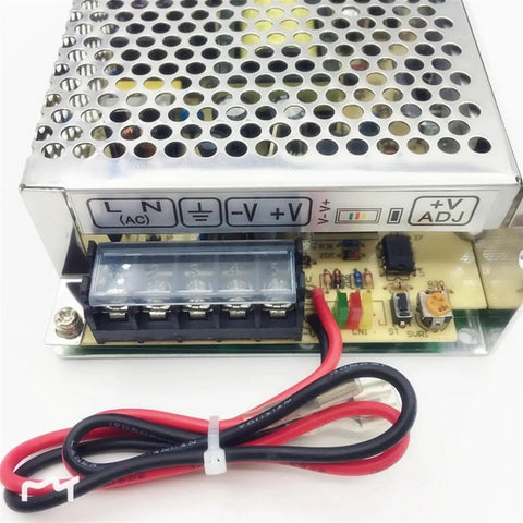 Close-up of a compact 60W switching power supply with UPS and charge function, input-output connections visible.