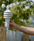 Hand installing Notos 3 In 1 Weather Station For Indoor Outdoor Temperature Humidity And Wind Speed With Real Time Readings Plus Hyperlocal Forecast On An Illuminated Color Display on a wooden fence