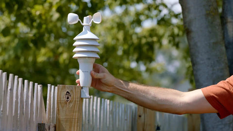 Hand installing Notos 3 In 1 Weather Station For Indoor Outdoor Temperature Humidity And Wind Speed With Real Time Readings Plus Hyperlocal Forecast On An Illuminated Color Display on a wooden fence