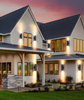 Modern house exterior with Two Pack Outdoor Wall Light With Slick Integrated LED Cylinder Up Down Lighting, illuminating walls and porch.