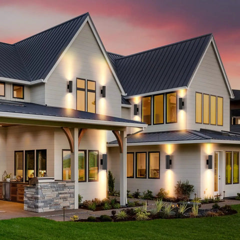 Modern house exterior with Two Pack Outdoor Wall Light With Slick Integrated LED Cylinder Up Down Lighting, illuminating walls and porch.