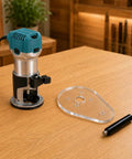 Score Your Shop Upgrade With This Six By Nine Inch Clear Acrylic Router Base Plate Built Straight For Makita Compact Models Featuring Pre Drilled Mounting Holes And Three Eighth Inch Thickness For Rock Solid Precision Woodworking on wooden table with router and handle.