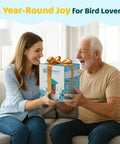 Smiling woman gifting 2K HD Bird Feeder Camera With Solar Power And 32GB Card Auto Detect And Notify AI ID 155 Degree Wide View Color Night Vision Wireless Outdoor Backyard Bird Feeder With 2.4G WiFi For Bird Lovers Gift to older man on couch.