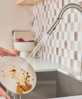 Top Shelf Pulldown Kitchen Faucet In Slick Spot Resist Stainless Steel washing food residue off a plate with 360 swivel spray wand.