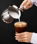 600ml Turkish Coffee Maker Stainless Steel Pot with Eagle Spout pouring milk into a coffee, showcasing easy pour function.