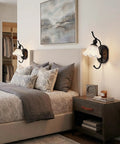 PUMING Black Wall Sconces Set of Two beside a bed, featuring flower glass shades and black metal frame in a cozy bedroom.