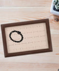 Solid Wood Earring Organizer And Ring Keeper Tray With Thirty Open Slots For Stashing Bracelets And Chains In A Rich Walnut Finish with a black bracelet.
