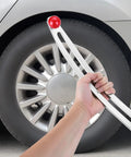 Hand holding hook rod from Car Dent Removal Tool Kit for DIY Auto Fender Repair against car tire backdrop