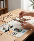 Hands assembling Beginner Friendly DIY Wooden Drone Kit With Full Protective Frame on table with electronics and wood pieces.