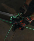 Boss Class 12V Max Three Plane Green Beam Laser Level in use, projecting green lines for precise alignment on flooring.
