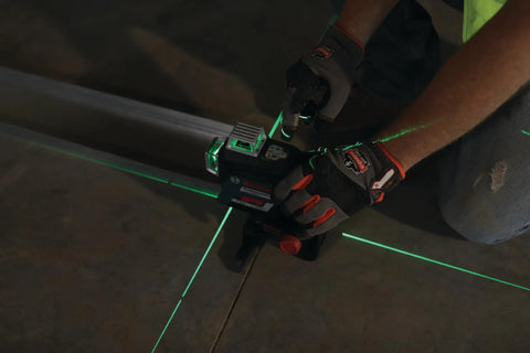 Boss Class 12V Max Three Plane Green Beam Laser Level in use, projecting green lines for precise alignment on flooring.
