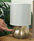 Transitional Small Touch Lamp Set in Antique Brass, 9.25 Inch Tall, shown on table with white shade beside a ruler and hand for scale