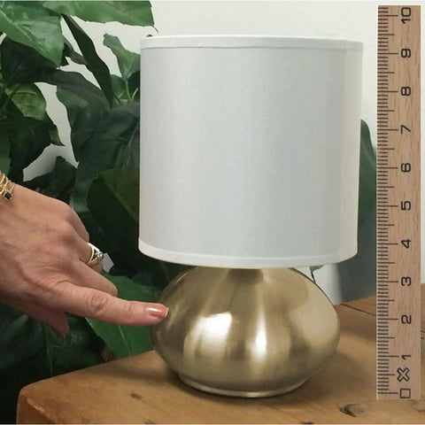 Transitional Small Touch Lamp Set in Antique Brass, 9.25 Inch Tall, shown on table with white shade beside a ruler and hand for scale