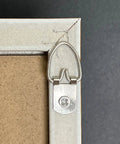 D ring hanger with slotted screw on frame corner, part of 100 Pack D Ring Picture Hangers With Screws For Hanging Frames Mirrors Clocks Paintings Ten Pound Load Support One And A Quarter Inch Long Five Eighths Inch Wide Bulk Pack Includes 100 Six By One Half Inch Slotted Phillips Combo Screws
