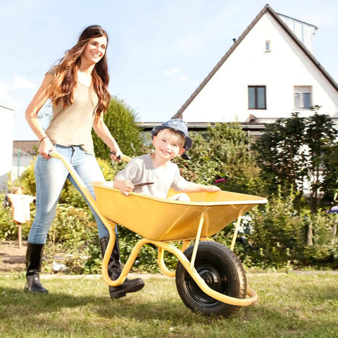 Woman pushing a wheelbarrow with a child, showcasing Go-To Universal 14.5 Inch Wheelbarrow Tire 3.50-8 with centered hub.