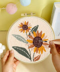 Punch Needle Embroidery Kit Beginner Friendly Two Pack With Tools Embroidery Hoops Two Pre Printed Fabrics And Color Threads Flower Pattern Set Tulip Bouquets And Sunflower Clusters DIY Home Decor Gift Project featuring a completed sunflower embroidery in a hoop.