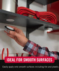 Hand applying Ultra Tough Industrial Hook And Loop Fasteners with Stick-On Adhesive, circular pad on a shelf for tool organization.