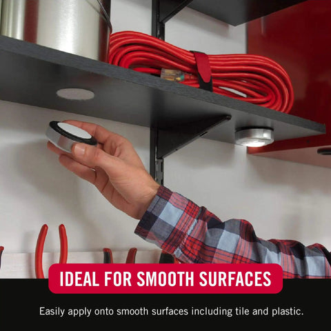 Hand applying Ultra Tough Industrial Hook And Loop Fasteners with Stick-On Adhesive, circular pad on a shelf for tool organization.