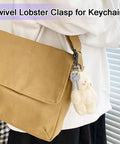 Heavy Duty Detachable Swivel Snap Hooks In Black Set Of Four Lobster Claw Clasps With Tight Grip Action for keychain on tan bag.