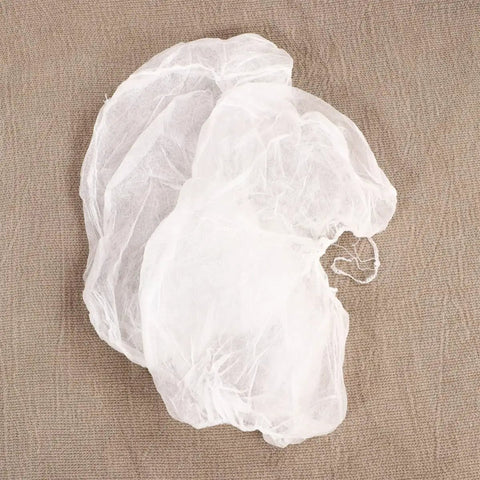 Straight Up Clean And No Drama Disposable Nonwoven Hair Covers With Tension Free Elastic Bands For Salon Beauty Chef Jobs And Long Daily Grind Sessions Pack Of 20 Fresh Caps, two caps showing soft white material on a textured background.