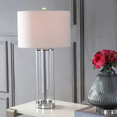 Clear Chrome Modern Glass Table Lamp For Living Room And Bedroom Slick Minimalist Nightstand Bedside Light With White Linen Drum Shade LED Bulb Included ETL Listed For Safe Clean Look on white table next to vase of pink flowers