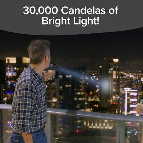 Man uses Monster Bright Rechargeable Spotlight With 10 Modes And Turbo Boost To 100 Percent Built In Kickstand And USB Phone Charger Ideal For Camping And Emergencies 9 Inch Black Flashlight As Seen On TV to illuminate city at night, showcasing its 30,000 candelas of brightness.