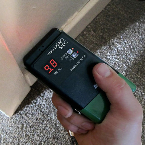 Person using S4-P And Mini-Ligno SD/C Moisture Meter And Mold Detector Kit With E14-M Electrode on wall corner for inspections.