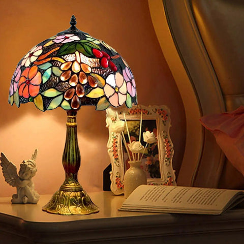 Tiffany Style Grape Rose Dope Stained Glass Table Lamp Handcrafted For Bedroom Living Room And Home Office Desk Decor With LED E26 Bulb Included 12x12x18 Inches illuminating a bedside table.