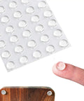 Top Shelf Clear Silicone Rubber Feet 100 Piece Pack Anti Skid Cabinet Bumpers Self Adhesive Picture Frame Protectors For Furniture And Appliances Rock Solid Dead Silent Non Slip Pad Set on a finger above a wooden surface.
