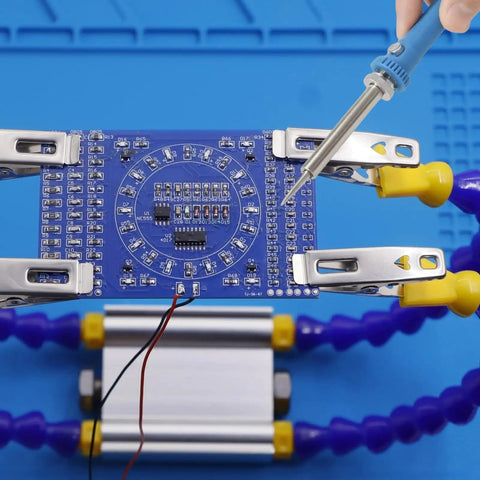 Beginner Friendly Soldering Practice Kit With 150 Electronic Components For Hands On Electronics Training Learn To Solder And Diagnose Faults On A Diy Practice Board showing a blue circuit board held by clips, being soldered.