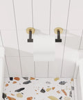 Matte Black And Brushed Brass Finish Double Post Pivoting Toilet Paper Holder Built Tough From SUS304 Stainless Steel Wall Mounted Tissue Holder For Commercial Bathrooms And RVs, mounted on white tile wall.