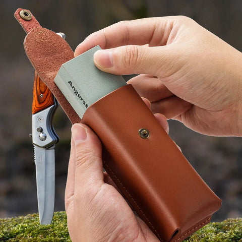 Person holding Portable Whetstone Knife Sharpener with Dual Grit 400/1000, pocket-knife, and cowhide pouch outdoors.