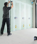 Pro Level 12V Green Beam Cross Line Laser With 100 Foot Reach in use for precision alignment on drywall installation.