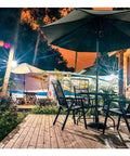60W LED Flood Light 6000LM Super Bright Outdoor Security Work Light illuminating a patio set and trees at night