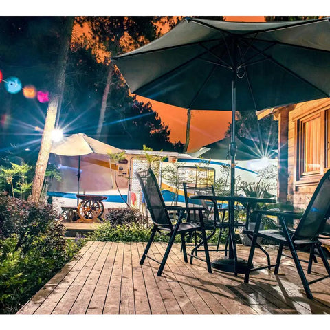 60W LED Flood Light 6000LM Super Bright Outdoor Security Work Light illuminating a patio set and trees at night