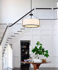 Grab This 20 Inch Drum Chandelier With 5 Lights For Instant Modern Farmhouse Vibes Featuring Soft White Linen Shades And Sleek Black Frames, hanging above a round wooden table.