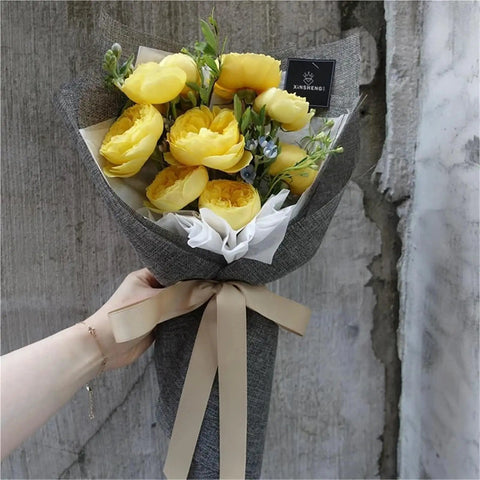 Hand holding yellow flower bouquet in Dope Bouquet Wrapping Paper 10 Yard Colored Linen Look Gift Wrap For Floral Arrangements.