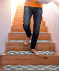 Person walking down wooden stairs with 15 Piece Non Slip Stair Treads For Wooden Steps Indoor Carpet Runner Rugs Mat 8x30 Inches Gray Diamond Pattern.