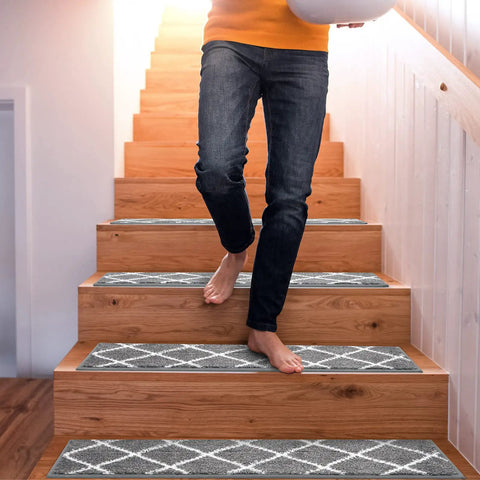 Person walking down wooden stairs with 15 Piece Non Slip Stair Treads For Wooden Steps Indoor Carpet Runner Rugs Mat 8x30 Inches Gray Diamond Pattern.