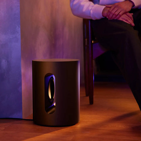 Sub Mini Compact Wireless Subwoofer For Beam And Ray with deep bass beside seated person, black finish